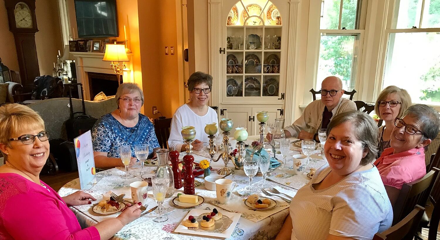 A group of ladies and one gentlemen gathered around a table for a special meal in a home