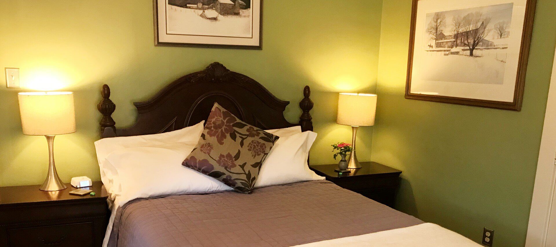 Elegant guest room with dark brown queen bed, green walls and two side tables with lamps